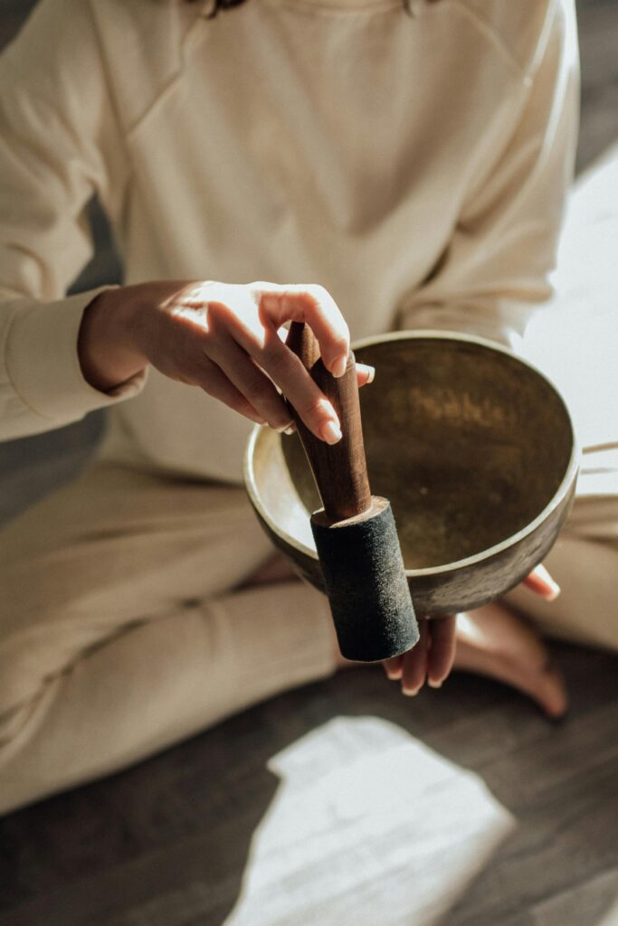 Close-up of hands holding a wooden pestle and grinding tool over a metal bowl or mortar.